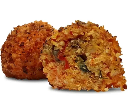 Arancino alla Norma tagliato a metà, ripieno con pomodoro e melanzane, accanto a un arancino intero