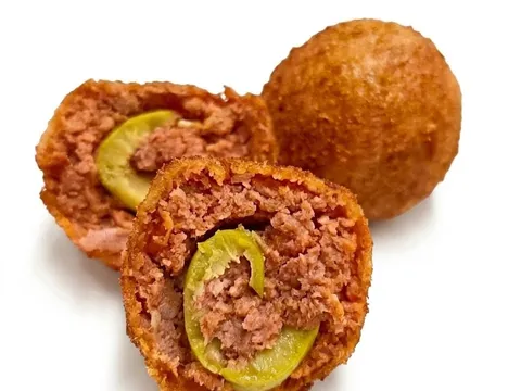 Olive ascolane impanate e fritte: una intera e due tagliate a metà, con il ripieno di carne e l'oliva verde